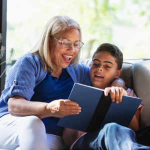 A woman in glasses reading to a young boy.
