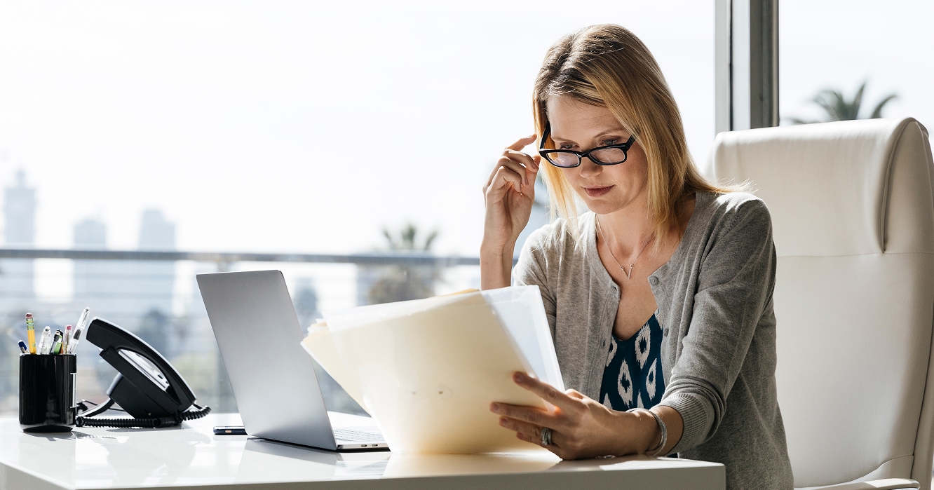 woman with glasses looking at papers