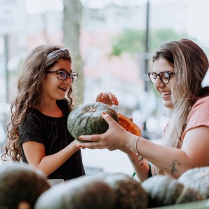 A mother and daughter pick produce.