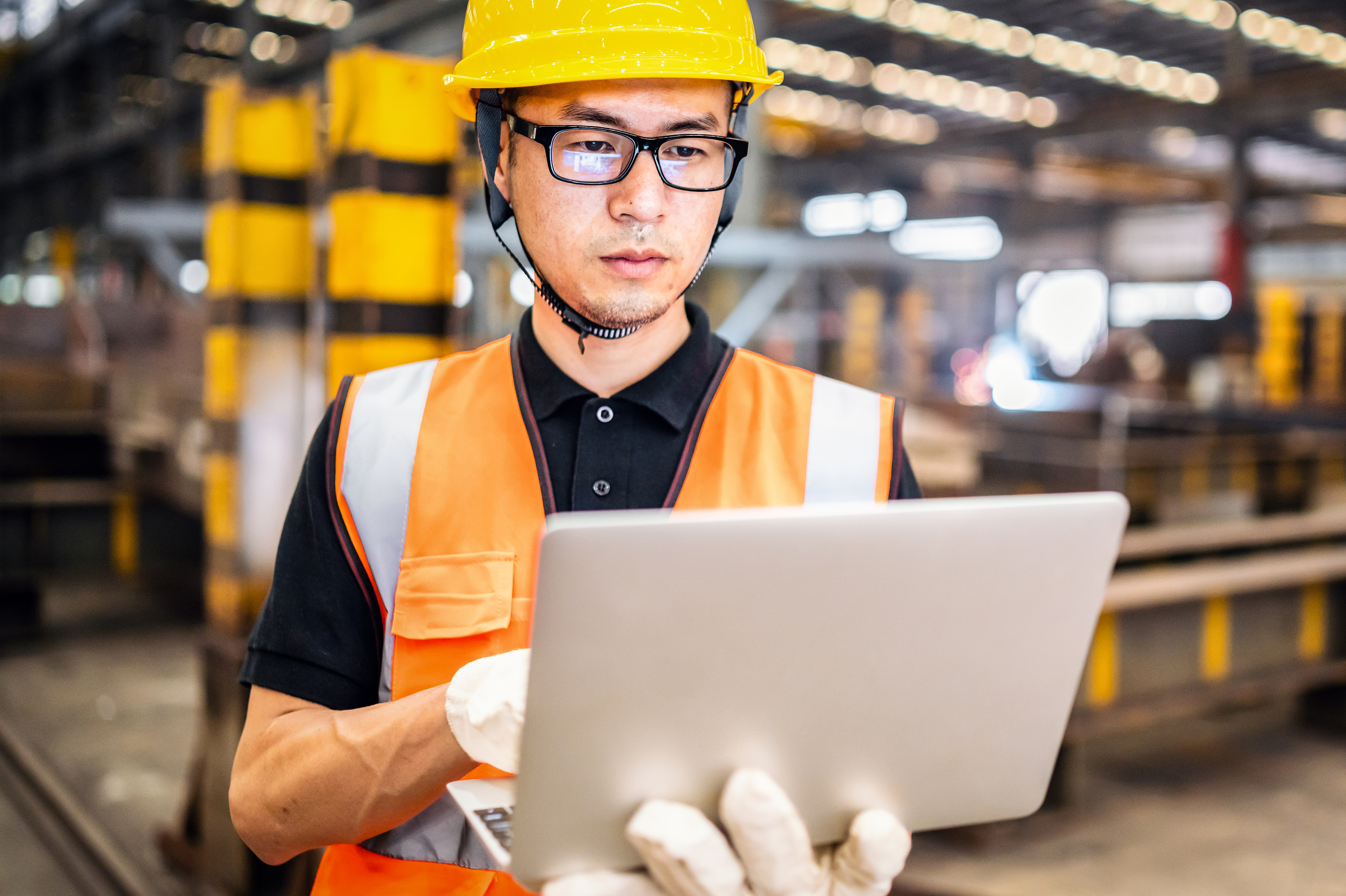man in a factory wearing glasses holding a tablet